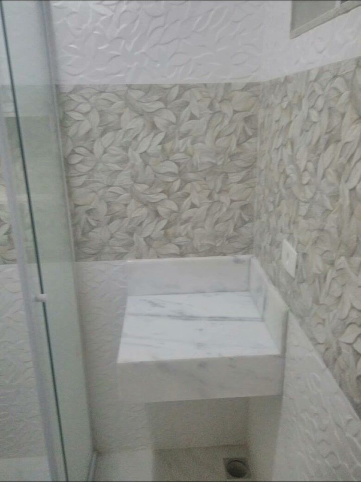 Banheiro pequeno com revestimento texturizado, bancada de mármore e box de vidro