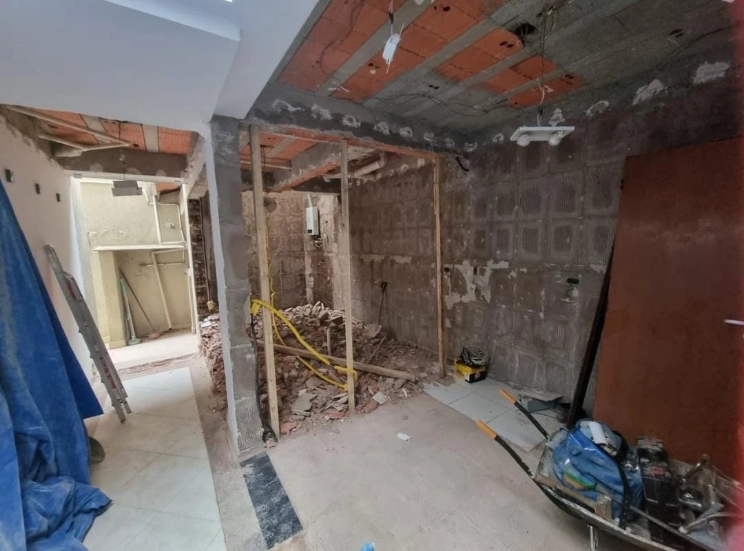 Antes: cozinha em obra, com paredes demolidas, laje aparente e entulho