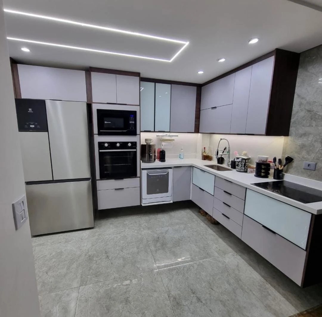 Depois: cozinha planejada com armários claros, eletros embutidos, bancada em L, cooktop e iluminação em LED no forro