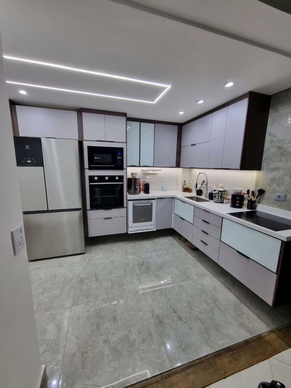 Cozinha planejada em L com faixas de iluminação em LED no teto, depois da reforma