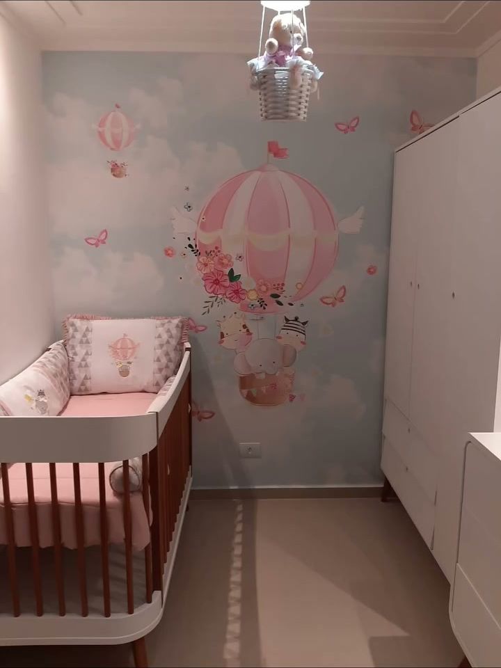 Quarto de bebê com papel de parede de balões, berço e luminária em formato de balão
