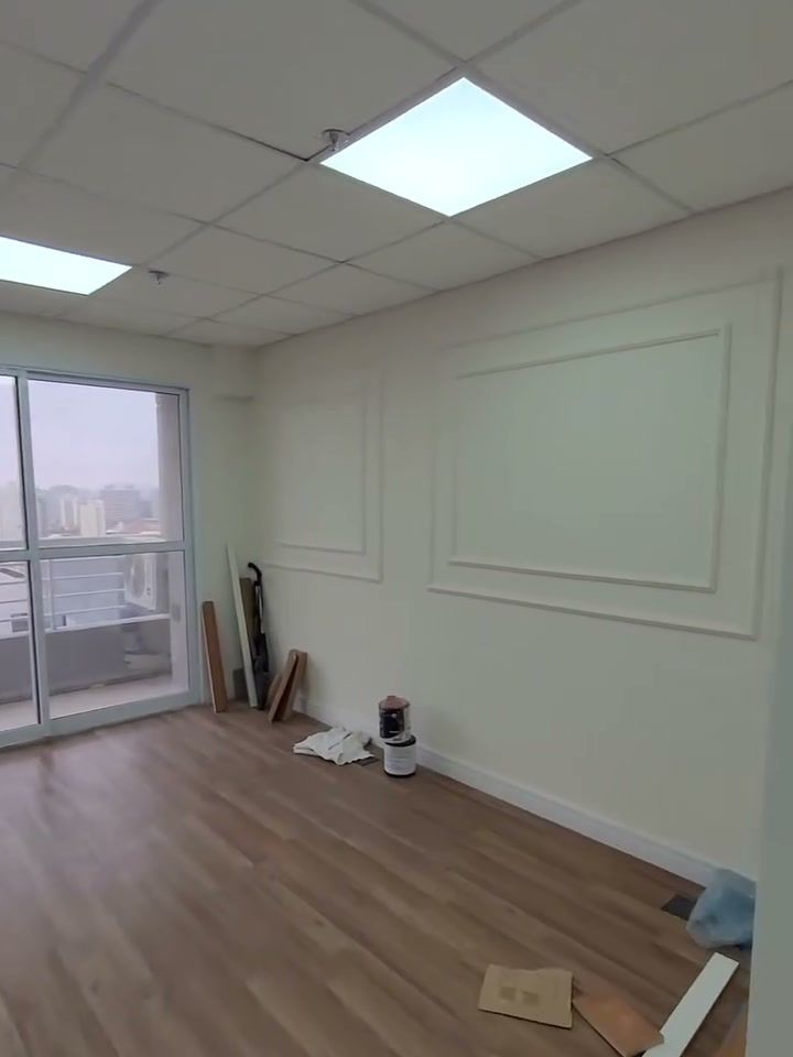 Sala comercial com piso de madeira, molduras nas paredes e janela panorâmica